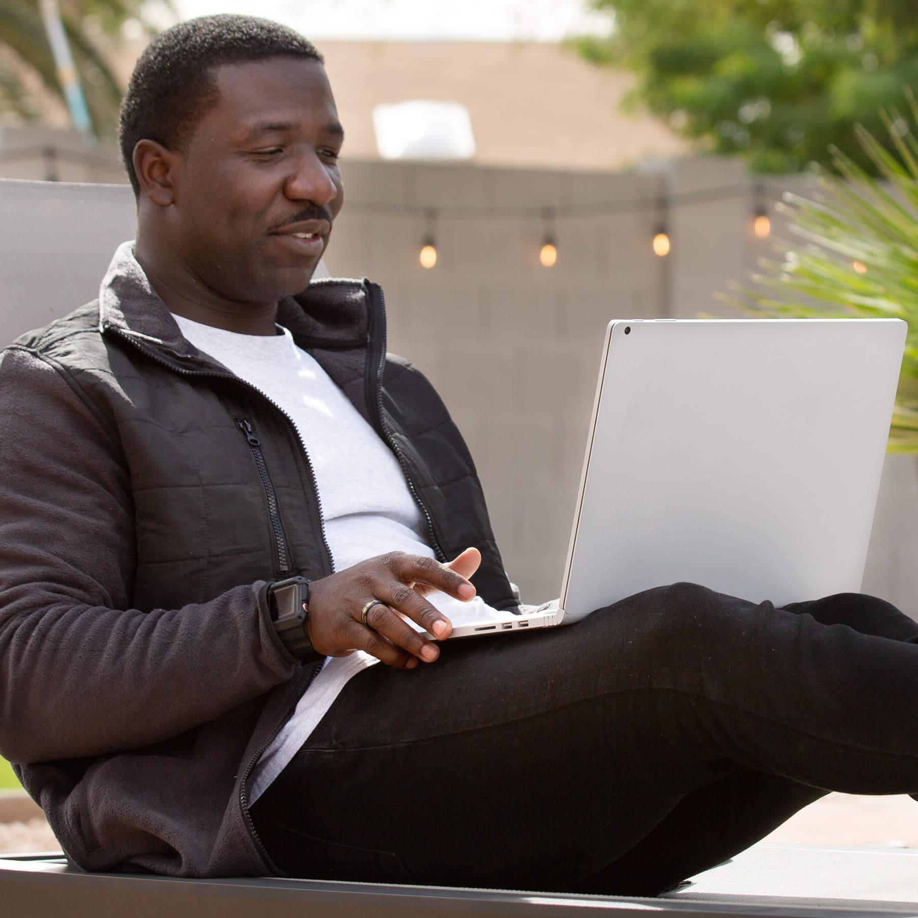 Jahmar罗宾逊 studying on his laptop, outside on a patio